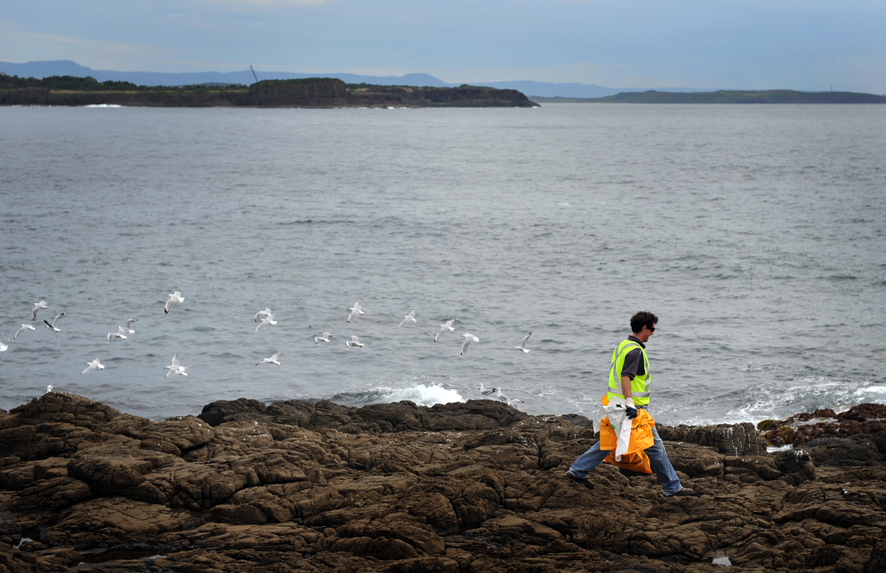 Council workers Byron Robinson cleans up rubish from between the rocks at Blowhole Point.