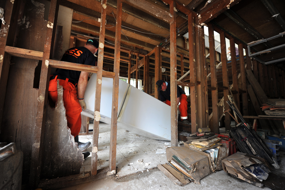 Shellharbour SES Rescue Warren De Wit and Deputy Controller David Berry remove a refrigerator from the damaged property in Graceville.